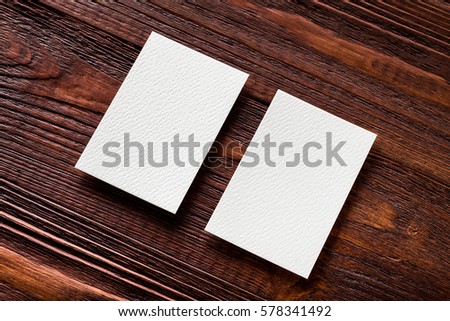 Closeup mockup of two blank vertical business cards at brown wooden table background.