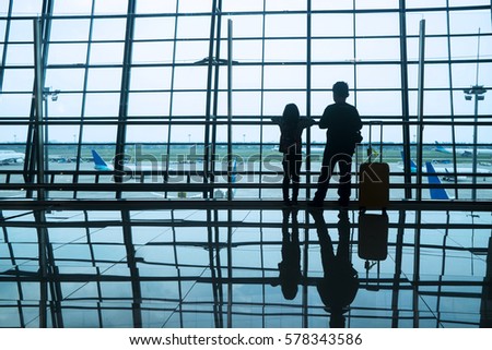 Silhouette of two children standing in the airport while looking at aircraft on the window