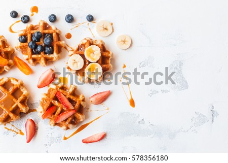 Traditional belgian waffles with fresh fruit and caramel on white background. Flat lay, top view, copy space. Royalty-Free Stock Photo #578356180