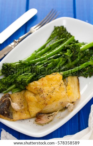 fried cod fish with greens on white plate