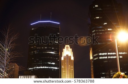 Night exterior of Minneapolis Minnesota skyline in downtown area. Skyscrapers light up midwest USA sky. Bright street lamp lens glare
