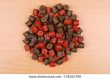 Brown with red pre-drilled halibut pellets for carp fishing isolated on wood background with soft shadow