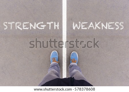 Strength and weakness text on asphalt ground, feet and shoes on floor, personal perspective footsie concept Royalty-Free Stock Photo #578378608
