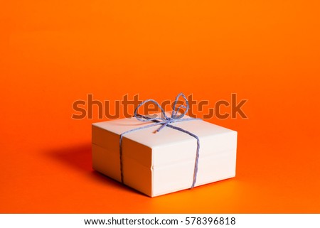 White gift box with bow on a orange background