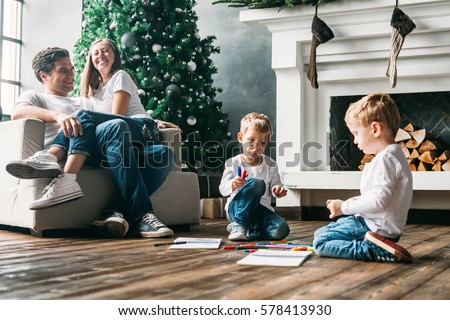 Children draw markers on the floor in the living room while the parents relax on the couch