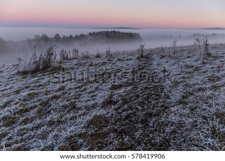 Frozen fields and woods overlooking Ore Mountains during sunset