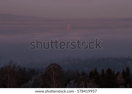 Frozen fields and woods overlooking Ore Mountains during sunset