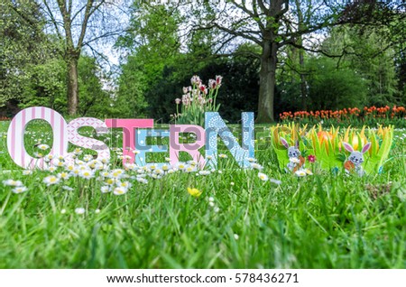 Decorative Easter inscription in German and basket with easter eggs in a meadow in the park