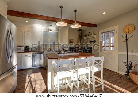 Newly renovated Kitchen boasts wood beams on ceiling, modern stainless steel appliances, white island with white x-back stools and hardwood floor. Northwest, USA
