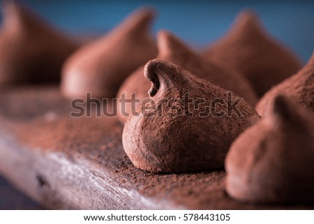 Assorted dark chocolate truffles with cocoa powder on dark blue table