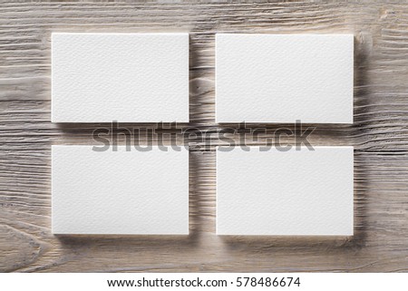 Closeup mockup of four blank vertical business cards at light natural wooden background.