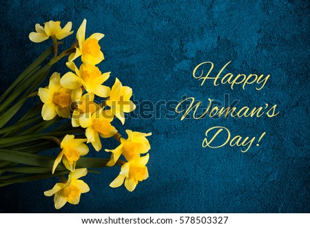 Beautiful Greeting Card with text Happy Women's Day for International Women's Day, March 8. Floral Background with Yellow Flowers daffodil on a navy blue texture. Top view, Flat lay. Horizontal Image