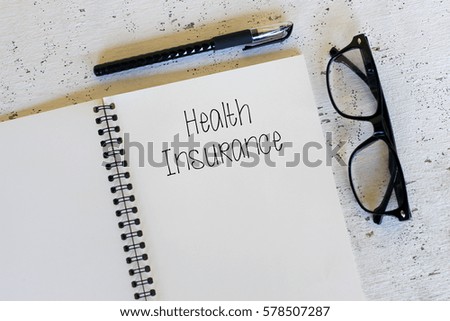 Business concept - Top view notebook writing Health Insurance