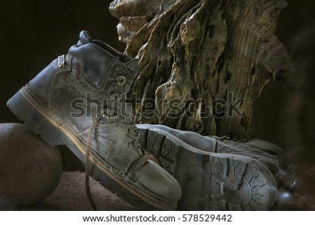Still Life Old Reliable men's boots in the dust on the background of wooden snag
