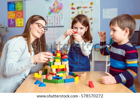 Teacher and Kids Playing Together with Colorful Toy Building Blocks Royalty-Free Stock Photo #578570272