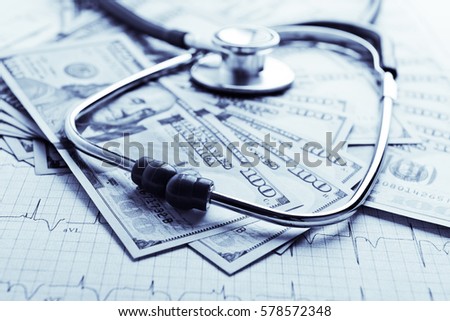 Dollars with stethoscope on them. Costs for the medical insurance. Blue toned