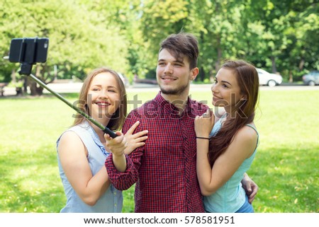 Group of young people are doing a self portrait to your mobile phone. A young man and two girls with pictures of the phone.