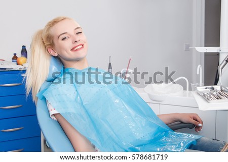 Girl in the dentist office sits in a chair with a smile