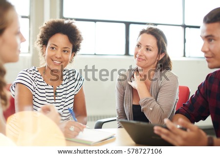 Unposed group of creative business entrepreneurs in an open concept office brainstorming together on a digital tablet. Royalty-Free Stock Photo #578727106