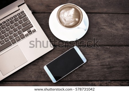Laptop or notebook and smartphone with cup of coffee on old wooden table