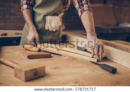 closeup photo of  cabinetmaker's tabletop.  Craftsman holding ruler  on wooden planknear other tools. Royalty-Free Stock Photo #578731717