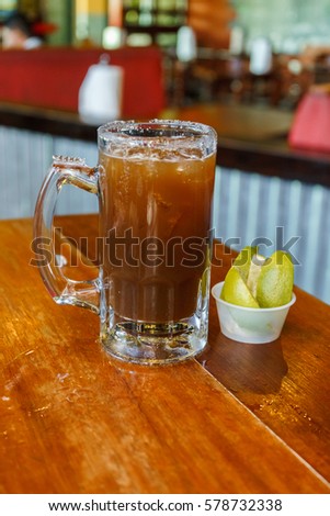 Glass of beer with mexican michelada mix and salt on the table.