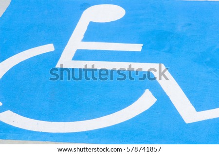 Close up detail of white on blue Handicapped in wheelchair sign and symbol on disabled car park