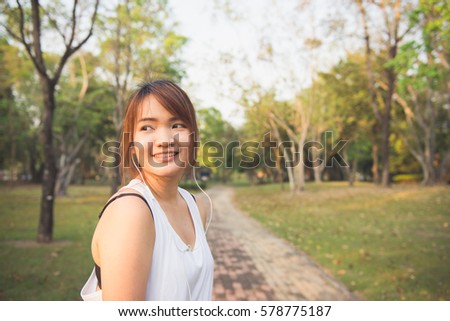 Happy sporty woman wearing smartphone armband and earphones before running in autumn. Female athlete listening music during fitness training outdoor. Vintage effect style pictures.