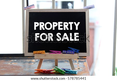 A Concept Image of a blackboard with a word PROPERTY FOR SALE and a small colorful clothespin on a rusty table surface over a blur bright background