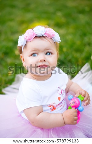 a beautiful child in a nice dress, with big blue eyes playing with toy
