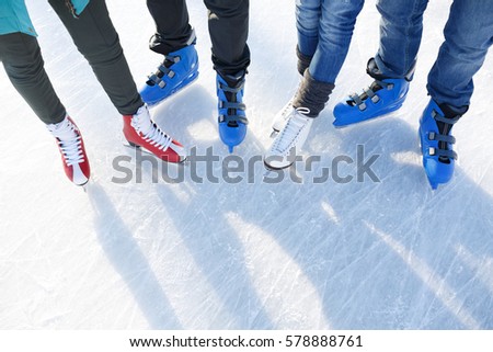 Closeup top view of legs in modern skates on ice rink.  Friends skating together outdoors  at winter frozen lake