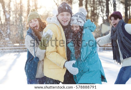 Winter holidays with friends. Group of young people spending great time together at snowy winter park while playing snowballs on frosty sunny day