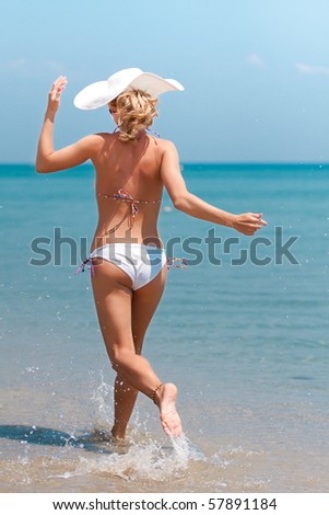 Young woman in bikini running on the beach