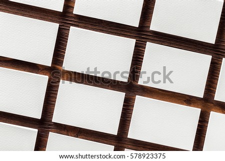 Mockup of blank business cards stacks arranged in rows at textured wooden table background.
