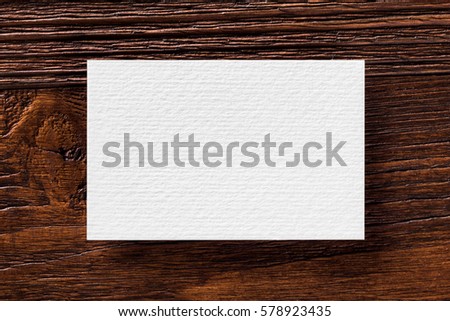Closeup mockup of blank business card at brown wooden table background.