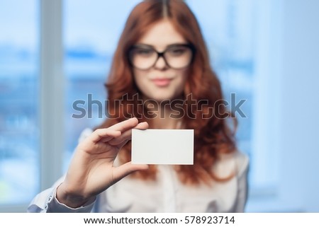 business woman with glasses wearing a white shirt against the backdrop of the city  brunette business card in the hands of.