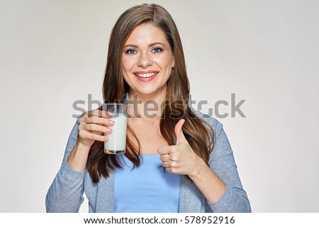 Smiling woman holding milk glass shows thumb up. Isolated portrait.