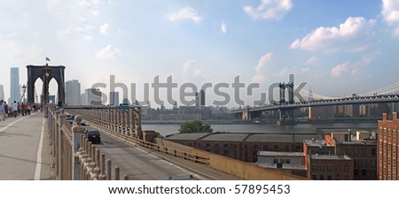 A panoramic image of the New York City skyline including the Brooklyn bridge the Manhattan bridge with the Empire State building in the far distance.