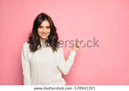 Cute young woman points a finger away Royalty-Free Stock Photo #578961391