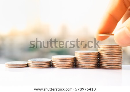 Man's hand put money coins to stack of coins. Money, Financial, Business Growth concept. Royalty-Free Stock Photo #578975413