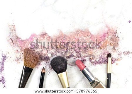 Makeup brushes, lipstick and pencil on a white background, with traces of powder and blush on it. A horizontal template for a makeup artist's business card or flyer design, with copy space