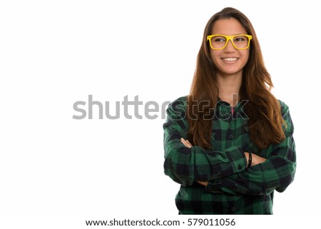 Studio shot of young happy woman smiling and thinking while wearing eyeglasses with arms crossed