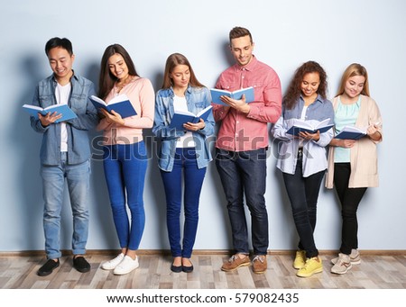 Group of people with books standing near light wall
