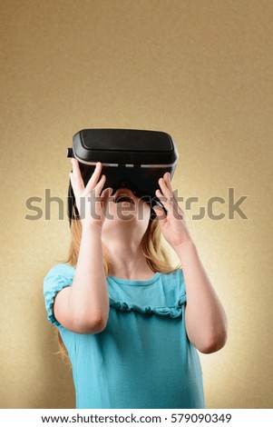 Little girl playing in virtual goggles indoors