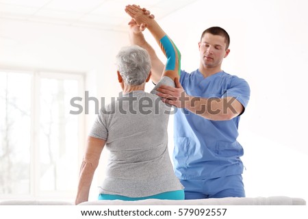 Physiotherapist working with elderly patient in clinic Royalty-Free Stock Photo #579092557