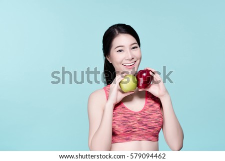 Asian woman with apples diet fruits concept. Fitness girl smiling and holding green and red apples. Beauty face and natural makeup sports bra outfit. Isolated over blue background