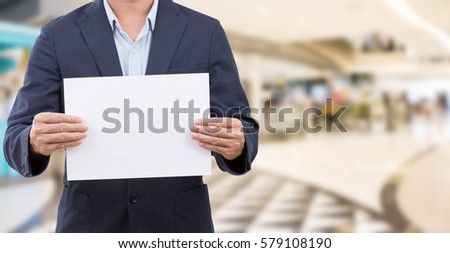 Man holding blank white board on blur shopping mall background