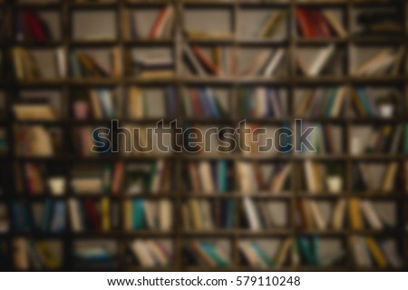 The background is a large bookshelf or book case on the wall. Many books in the side. Blurred background. The place to insert the text.