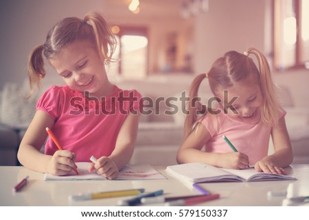 Two little girls drawing at home.