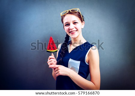 Funny girl eating lollipop on a blue background, studio